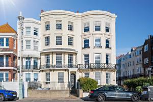 a large white building with a car parked in front of it at Premium Beach Front with Balcony! 2 En-Suites & Spacious By Stay Aura Vacation Rental Brighton & Hove in Brighton & Hove