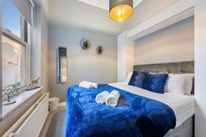 a bedroom with a blue bed with towels on it at Premium Beach Front with Balcony! 2 En-Suites & Spacious By Stay Aura Vacation Rental Brighton & Hove in Brighton & Hove