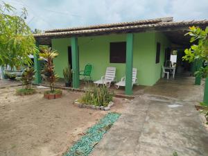 a green house with chairs and a patio at Recanto Dunas Santa Rita in Estância