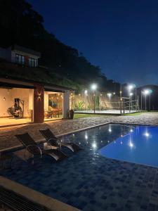 a swimming pool at night with chairs and lights at Chalé São Bernardo, Carmo RJ in Carmo