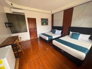 a hotel room with two beds and a desk at Hotel Wilson Ciudad Neily in Neily