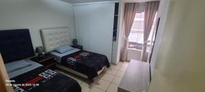 a small room with two beds and a window at Departamento Centenario in Lima