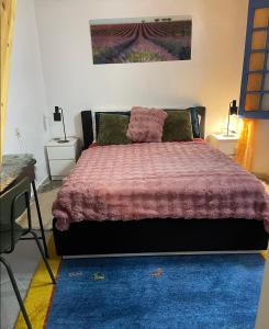 a bedroom with a bed with a purple blanket and a desk at Meryem Appartement in Essaouira