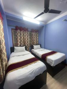 two beds in a room with blue walls at New milan guest house in Kathmandu