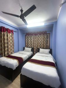 two beds in a room with blue walls and a ceiling at New milan guest house in Kathmandu