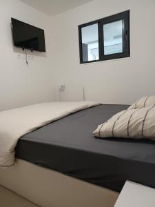 a bedroom with a bed with a tv on the wall at Le Doudou, Charmant T2 avec Terrasse et Climatisation in Marmande