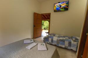 a bedroom with two beds and a tv on the wall at Pousada Morada do Paraíso in Torrinha