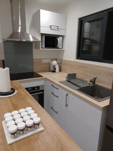 a kitchen with white cups on a counter with a sink at Le Doudou, Charmant T2 avec Terrasse et Climatisation in Marmande