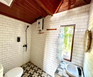 a bathroom with a toilet and a sink and a window at KeJogja Homestay in Grigak +38 photos
