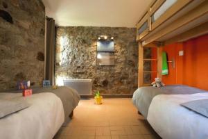 a bedroom with two beds and a stone wall at ZEcamping 3 étoiles animaux acceptés piscine et Canoë Kayak in Chambonas