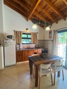 a kitchen with a table with chairs and a refrigerator at Cabaña La Pinta in Santa Teresita