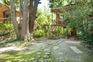 a house with a tree and a walkway next to it at Cabaña Los Alcanfores in Tigre