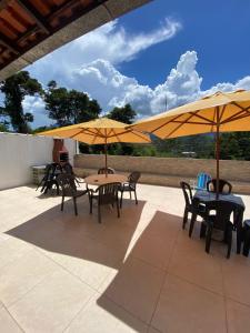 a patio with tables and chairs with umbrellas at Pousada Por do Sol in Teresópolis