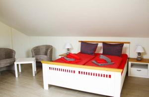 a bedroom with a red bed with two chairs at Sonnenschein in Lenz