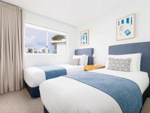 two beds in a hotel room with a window at Mantra Zanzibar in Mooloolaba +82 photos