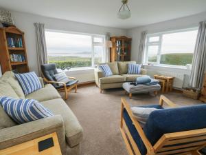 a living room with couches and chairs and windows at Yr Orsedd in Holyhead
