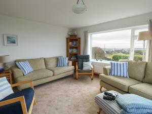 a living room with couches and a large window at Yr Orsedd in Holyhead