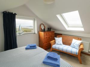 a bedroom with a bed and a chair and a window at Yr Orsedd in Holyhead