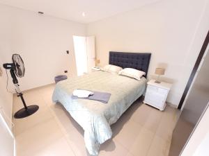 a white bedroom with a bed and a fan at Brisa Austral Comodoro in Comodoro Rivadavia