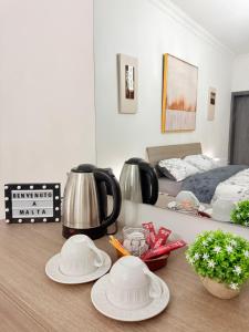 a table with plates and a tea kettle and a bed at Room in sliema's heart in Il-Gżira