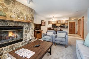 a living room with a stone fireplace and two chairs at Townsend Place, A Vail Resorts Property in Beaver Creek