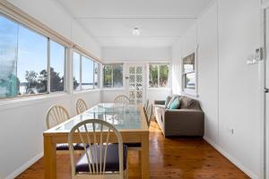 a dining room with a table and chairs and a couch at Sunbeam Cottage on the Lake in Toukley