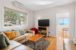 a living room with a couch and a flat screen tv at Sunbeam Cottage on the Lake in Toukley