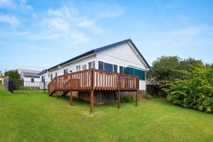 a house with a large deck in the yard at Sunbeam Cottage on the Lake in Toukley