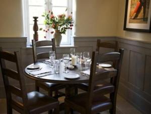 a wooden table with chairs and glasses on it at The Bell at Hampton Poyle in Kidlington