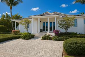 a white house with a palm tree at Amamare Waterfront Villa | Pool + Private Dock in Bailey Town
