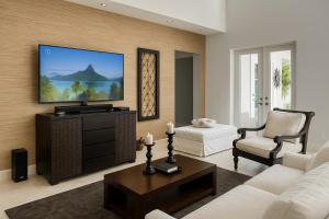 a living room with a couch and a tv at Amamare Waterfront Villa | Pool + Private Dock in Bailey Town +40 photos
