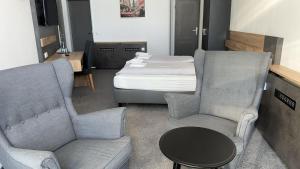 a room with two chairs and a bed and a table at Hotel Belvedere in Seevetal