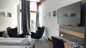 a bedroom with a bed and chairs and a flat screen tv at Hotel Belvedere in Seevetal