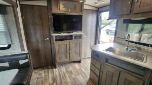 a kitchen in an rv with a sink and a tv at Rattrays Rd Farm Accomodation in Makikihi