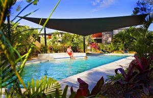 a woman in a swimming pool with an umbrella at Breakaway • Central Studio for 4 • Beach • Pool in Agnes Water