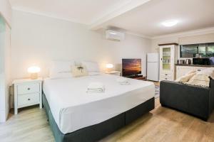 a bedroom with a large white bed and a couch at Merindah • Pet-Friendly • Central 4BDR for 10 in Agnes Water