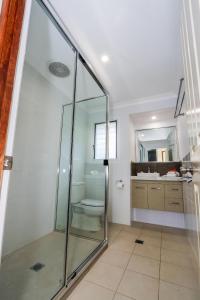 a bathroom with a glass shower and a toilet at McLeods • Pet-Friendly Central Beach House for 6 in Agnes Water +30 photos