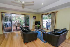 a living room with two leather couches and a television at McLeods • Pet-Friendly Central Beach House for 6 in Agnes Water