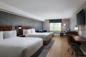a hotel room with two beds and a desk at Four Points by Sheraton Austin Airport in Austin