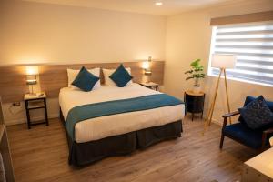 a bedroom with a large bed and a blue chair at Hotel Auramia in Punta Arenas