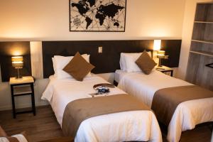 a hotel room with two beds and two lamps at Hotel Auramia in Punta Arenas