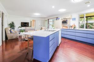 a kitchen with blue cabinets and a white counter top at On Agnes Time • Beach House for 10 • BBQ Deck • Walk to Beach in Agnes Water