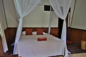 a bedroom with a white bed with curtains at Rimba Orangutan Ecolodge in Kampungcina