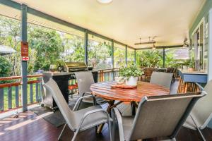 a balcony with a wooden table and chairs at On Agnes Time • Beach House for 10 • BBQ Deck • Walk to Beach in Agnes Water