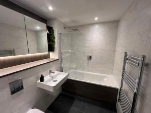 a bathroom with a sink and a tub and a toilet at Luxe Penthouse 2 bed Deansgate in Manchester +7 photos