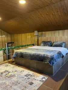 ein Schlafzimmer mit einem großen Bett und einer Holzdecke in der Unterkunft Aroma Chalet in Ḩūmīn al Fawqā