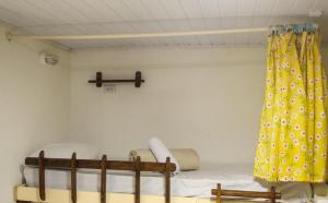 a bed in a room with a yellow curtain at Artetude Hostel Cultural in Barra de Guaratiba +87 photos