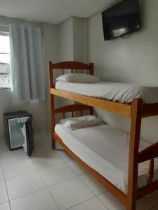 a room with three bunk beds and a television at Hotel Algaroba Anexo in Bom Jesus da Lapa