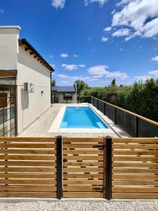 a swimming pool with a wooden fence next to a house at Lirios del Cerro in Sierra de la Ventana