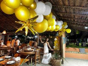 a woman standing under a bunch of yellow and white balloons at POUSADA PONTA DA ASA in Coruripe +149 photos